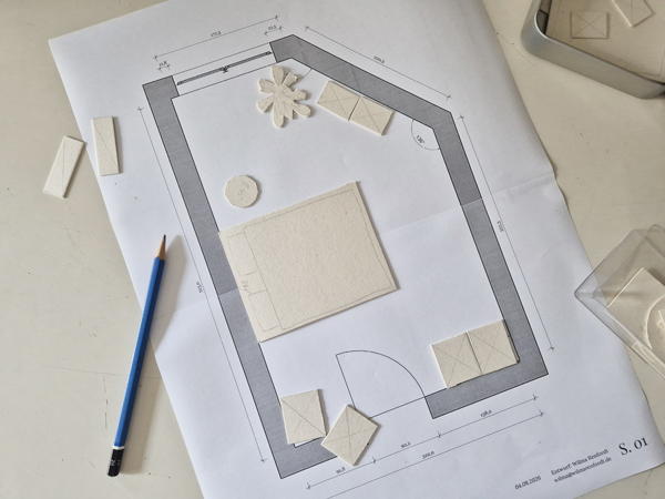 ein Blatt Papier mit einem ausgedruckten Grundriss und Möbel-Symbolen aus Pappe